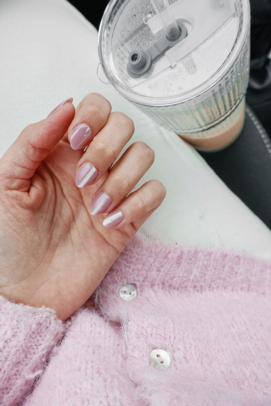 Pastel manicure holding a glass of smoothie in a cozy sweater